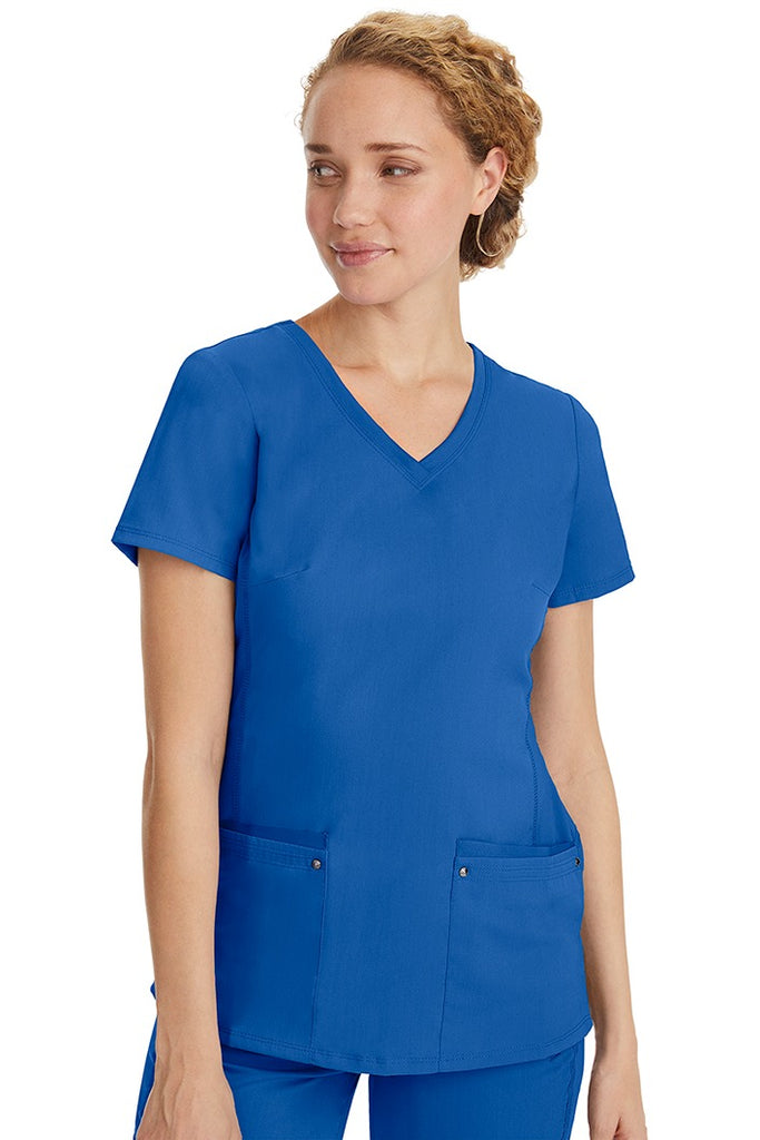 A female healthcare professional wearing a Women's Juliet Yoga Scrub Top from Purple Label in Royal featuring a side stretch panels.