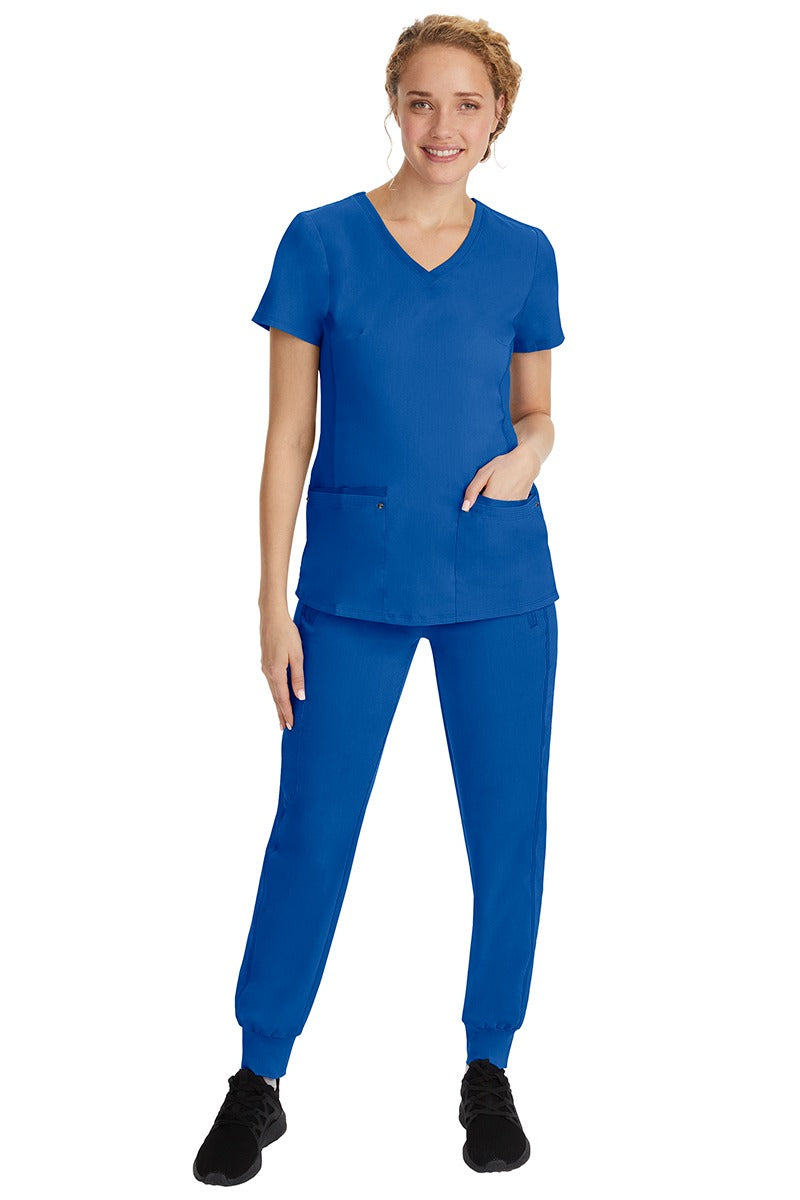 A young female nurse wearing a Purple Label Women's Juliet Yoga Scrub Top by Healing Hands in Royal featuring a v-neckline.