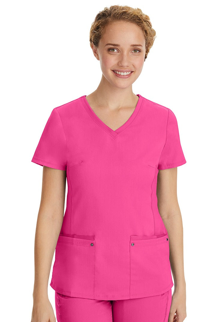 A young LPN wearing a Purple Label Women's Juliet Yoga Scrub Top in Shocking Pink featuring 2 front patch pockets.