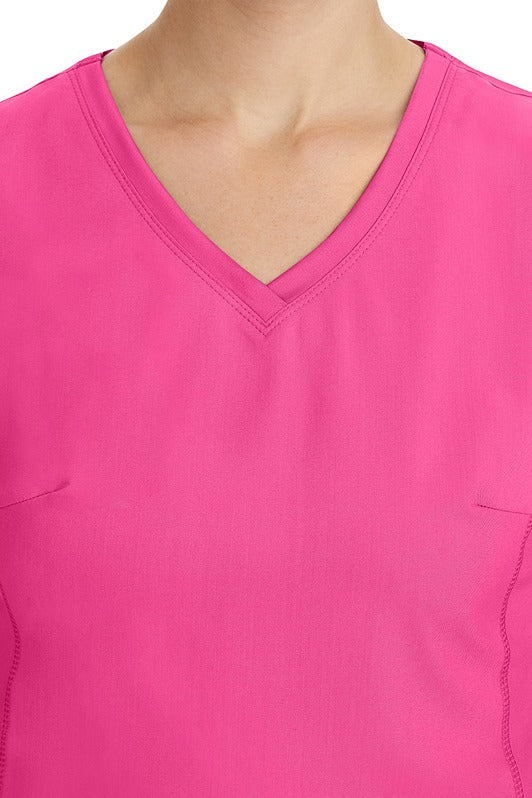A young healthcare professional wearing a Purple Label Women's Juliet Yoga Scrub Top in Shocking Pink featuring a modern fit.