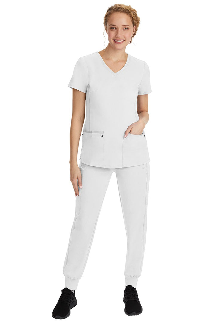 A young female nurse wearing a Purple Label Women's Juliet Yoga Scrub Top by Healing Hands in White featuring a v-neckline.
