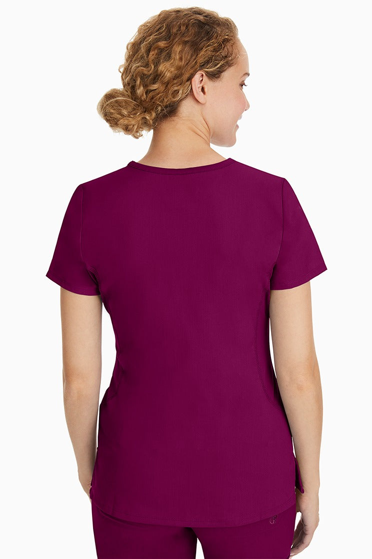 A female CNA wearing a Purple Label Women's Juliet Yoga Scrub Top in Wine featuring a medium center back length of 24".
