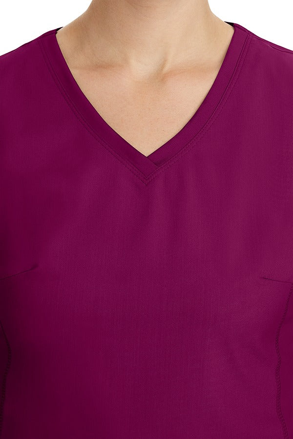 A young healthcare professional wearing a Purple Label Women's Juliet Yoga Scrub Top in Wine featuring a modern fit.