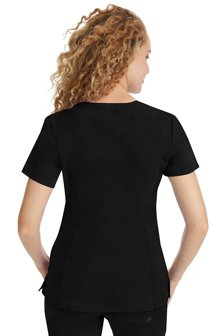 A young woman wearing a Purple Label Women's Jasmin Fashion V-neck Scrub Top in Black featuring a center back length of 25.5".