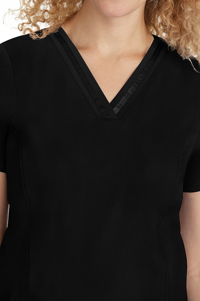 A young lady CNA wearing a Purple Label Women's Jasmin Fashion V-neck Scrub Top in Black featuring a super comfortable stretch fabric made of 96% polyester & 6% spandex.
