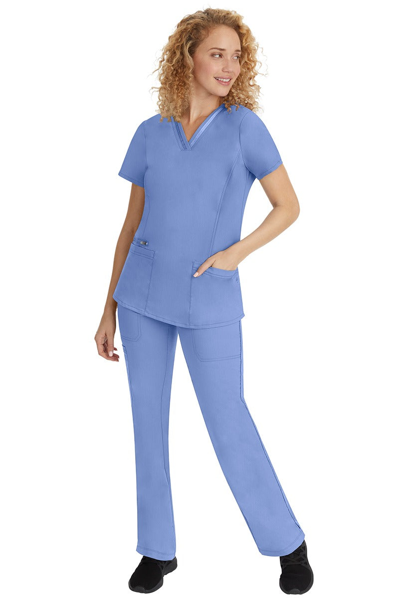 A young lady nurse wearing a Purple Label Women's Jasmin Fashion V-Neck Scrub Top in Ceil with a missy relaxed fit & short sleeves.