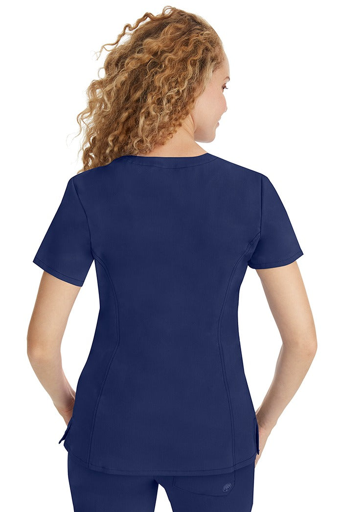 A young woman wearing a Purple Label Women's Jasmin Fashion V-neck Scrub Top in Navy featuring a center back length of 25.5".