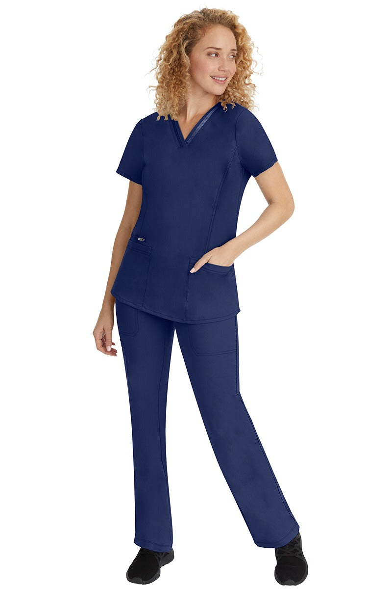 A young lady nurse wearing a Purple Label Women's Jasmin Fashion V-Neck Scrub Top in Navy with a missy relaxed fit & short sleeves.