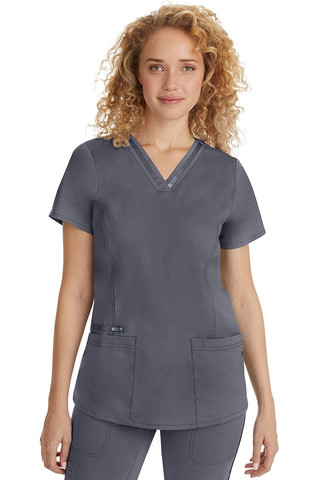 A female Nurse Practitioner wearing a Purple Label Women's Jasmin Fashion Scrub Top in Pewter featuring a trimmed v-neckline.