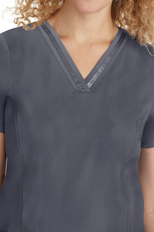 A young lady CNA wearing a Purple Label Women's Jasmin Fashion V-neck Scrub Top in Pewter featuring a super comfortable stretch fabric made of 96% polyester & 6% spandex.