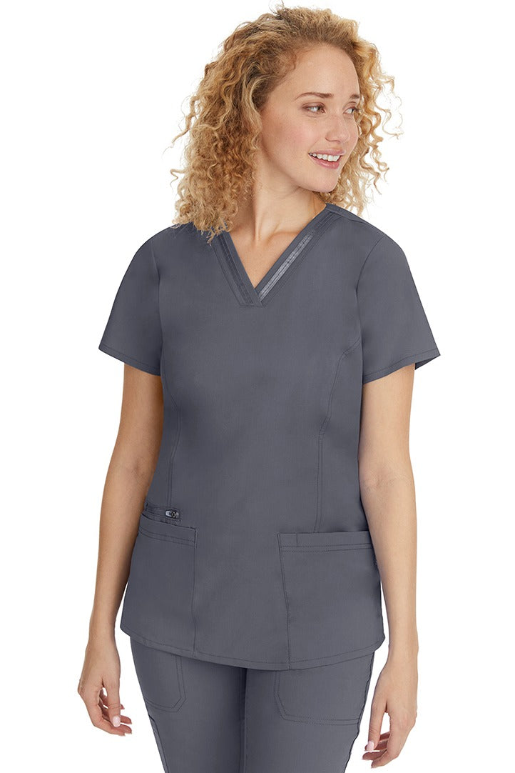 A young Home Care Registered Nurse wearing a Purple Label Women's Jasmin Fashion V-Neck Scrub Top in Pewter featuring front & back princess seams to provide a flattering fit.