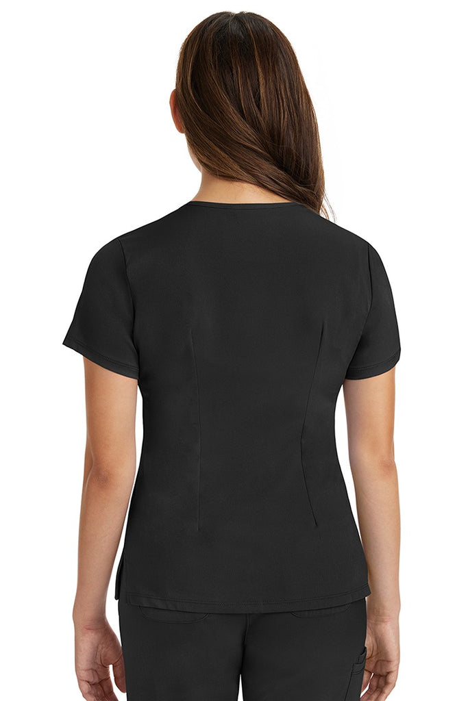 A female registered nurse wearing a Women's Monica Multi-Pocket Scrub Top from HH Works in Black featuring back princess darts for shaping.