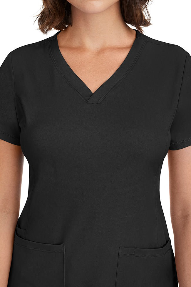 A young woman CNA wearing a HH-Works Women's Monica Multi-Pocket Scrub Top in Black featuring front princess seaming to ensure a flattering fit.