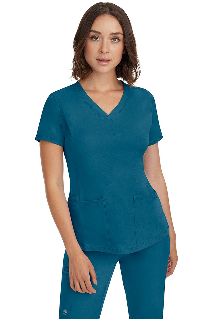 A female Nurse Practitioner wearing an HH-Works Women's Monica Multi-Pocket Scrub Top in Caribbean featuring a total of 4 pockets.