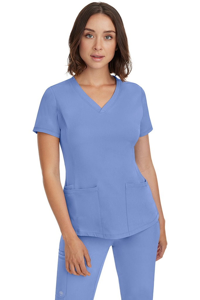 A female Nurse Practitioner wearing an HH-Works Women's Monica Multi-Pocket Scrub Top in Ceil featuring a total of 4 pockets.