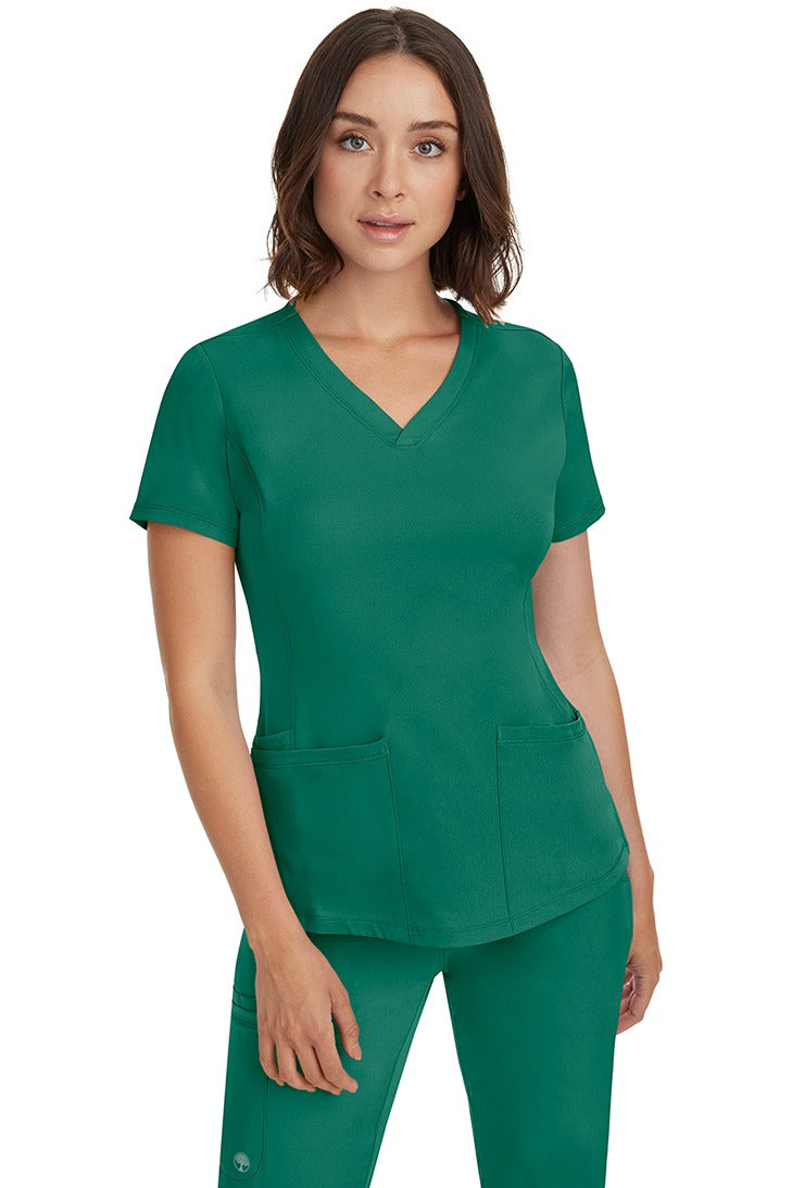 A female Nurse Practitioner wearing an HH-Works Women's Monica Multi-Pocket Scrub Top in Hunter Green featuring a total of 4 pockets.