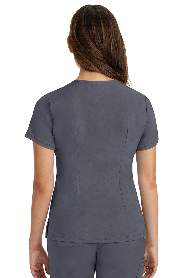 A female registered nurse wearing a Women's Monica Multi-Pocket Scrub Top from HH Works in Pewter featuring back princess darts for shaping.
