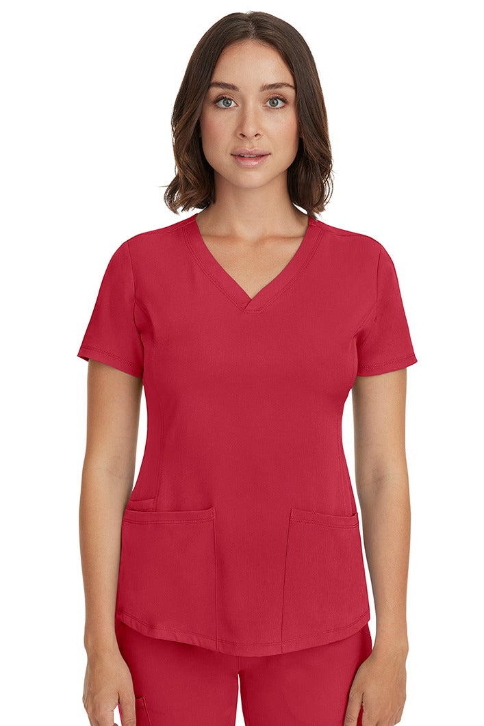 A young female LPN wearing a HH-Works Women's Monica Multi-Pocket Scrub Top in Red featuring short sleeves & a v-neckline.