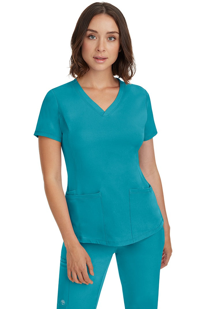A female Nurse Practitioner wearing an HH-Works Women's Monica Multi-Pocket Scrub Top in Teal featuring a total of 4 pockets.