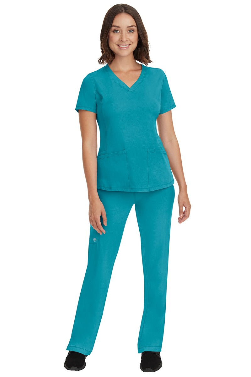 A young female nurse wearing a Women's Monica Multi-Pocket Scrub Top from HH Works in Teal featuring unique stretch fabric made of 91% polyester & 9% spandex.