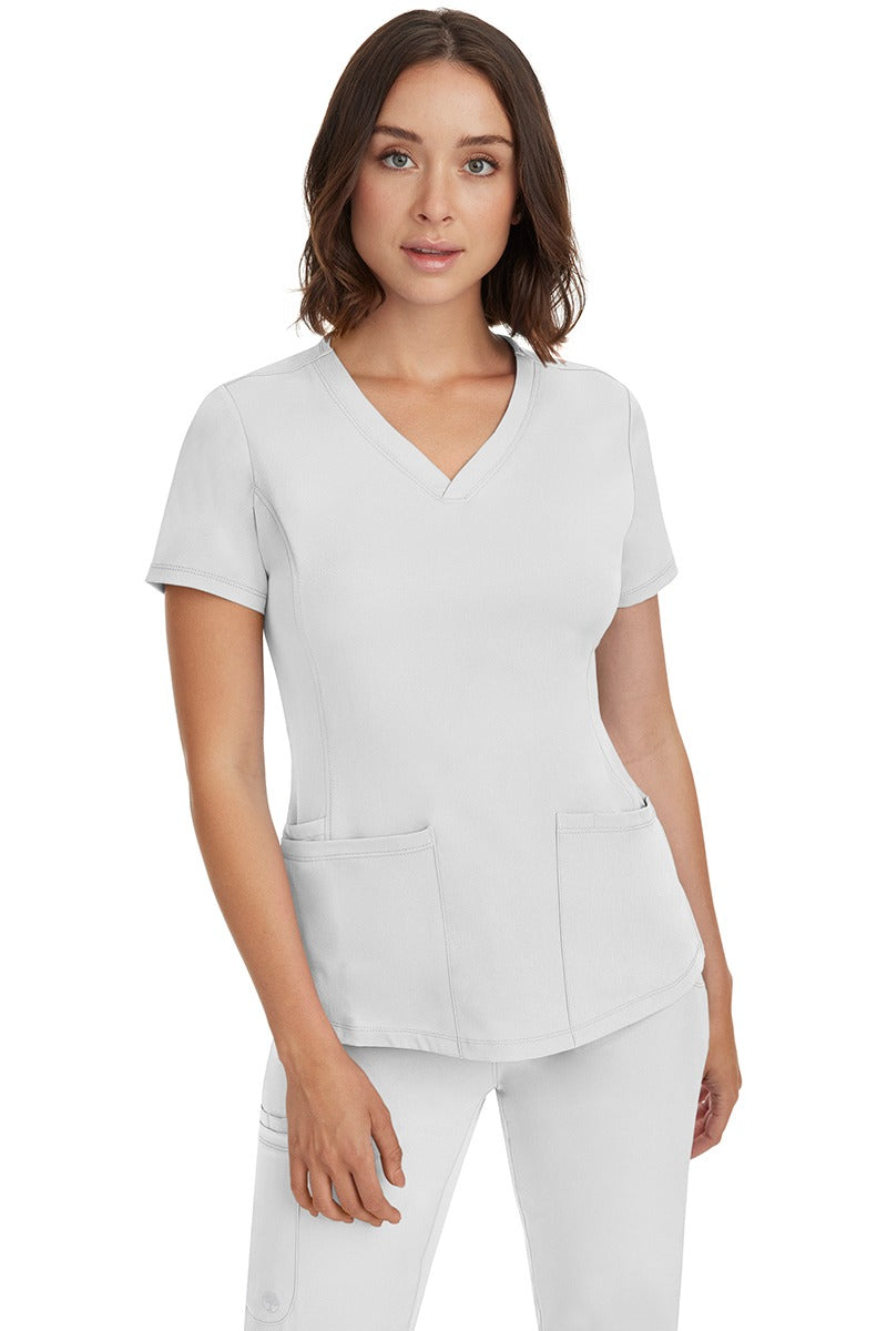 A female Nurse Practitioner wearing an HH-Works Women's Monica Multi-Pocket Scrub Top in White featuring a total of 4 pockets.