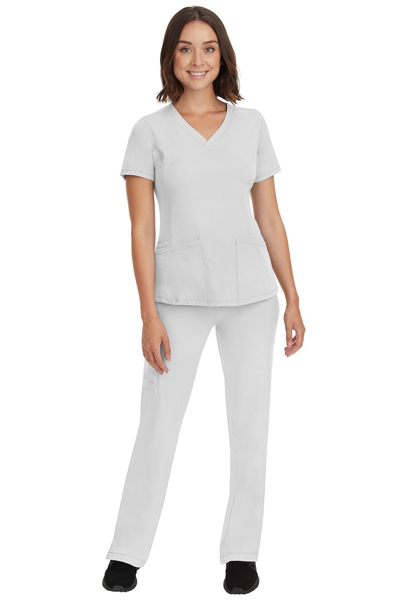 A young female nurse wearing a Women's Monica Multi-Pocket Scrub Top from HH Works in White featuring unique stretch fabric made of 91% polyester & 9% spandex.
