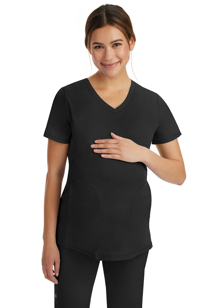 A pregnant female LPN wearing an HH-Works Women's Mila Maternity V-Neck Scrub Top in Black featuring a v-neckline & short sleeves.