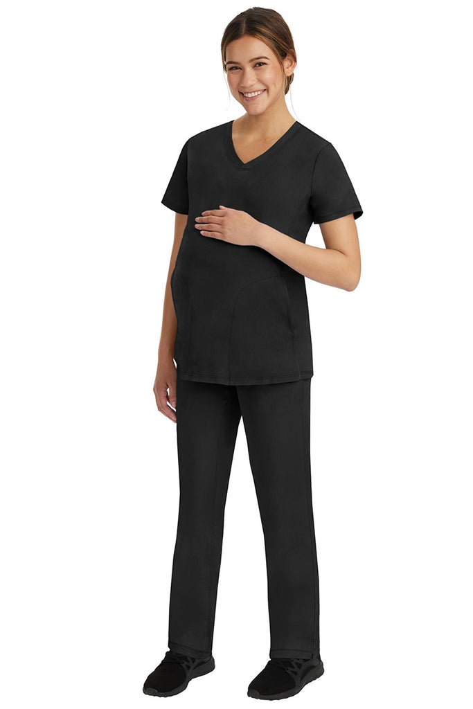 A young female healthcare worker wearing a HH-Works Women's Mila Maternity V-Neck Scrub Top in Black featuring a unique stretch fabric made of 91% Polyester & 9% Spandex.