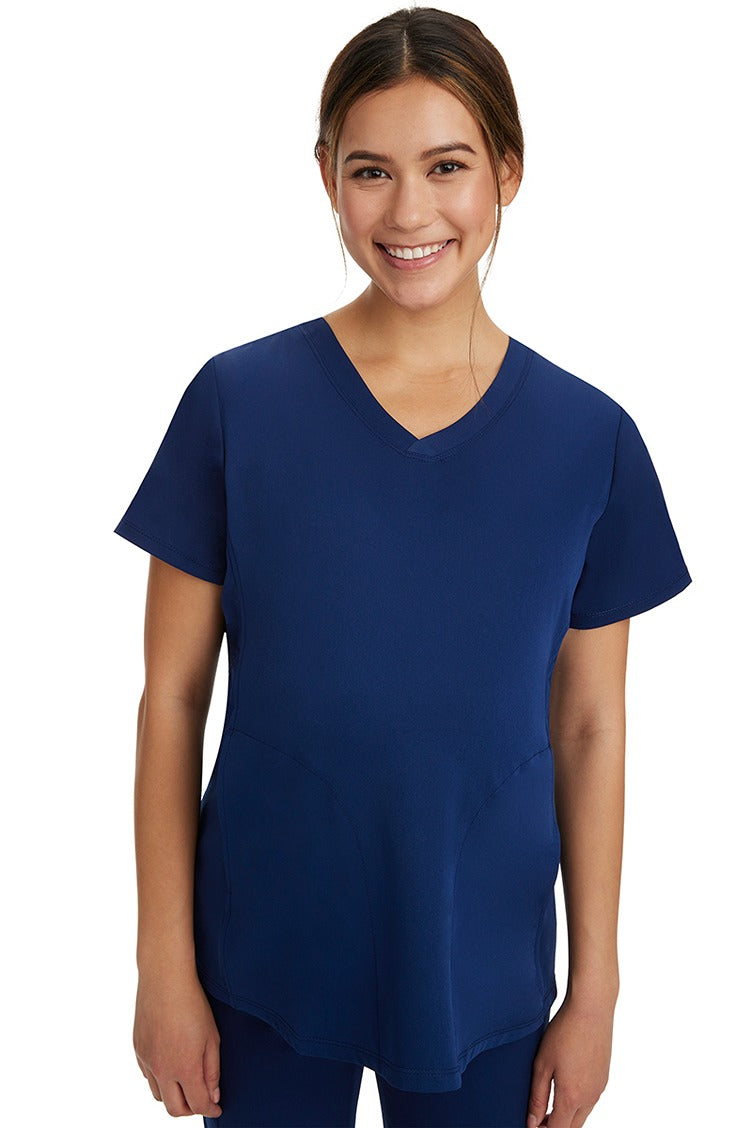 A pregnant female LPN wearing an HH-Works Women's Mila Maternity V-Neck Scrub Top in Navy featuring a v-neckline & short sleeves.