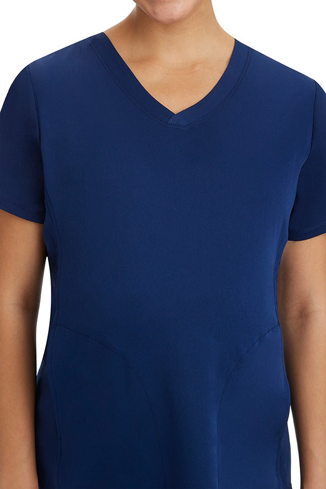 A female Registered Nurse wearing an HH-Works Women's Mila Maternity V-Neck Scrub Top in Navy  featuring a a draped hemline.