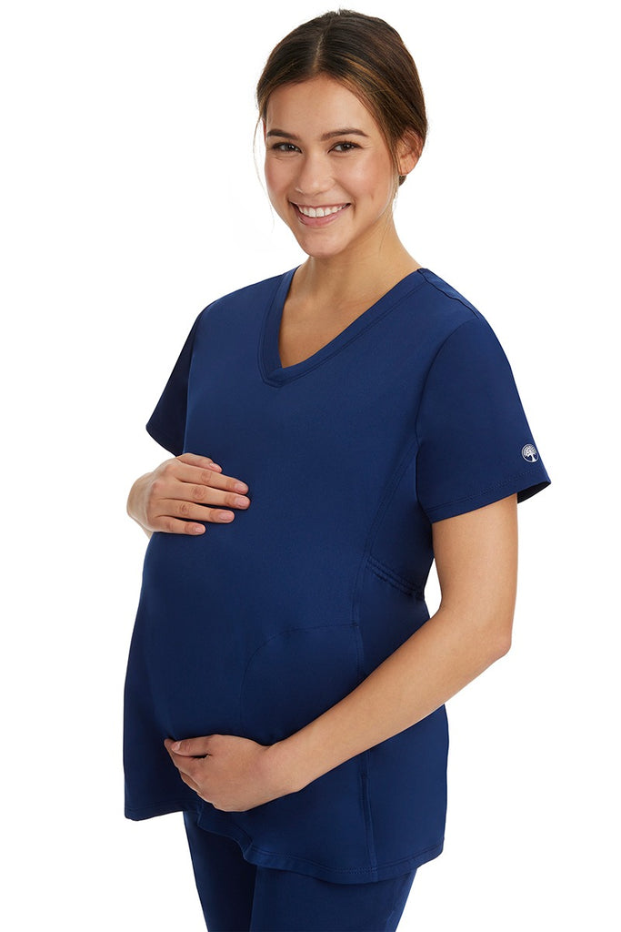 A lady Home Care Registered Nurse wearing an HH-Works Women's Mila Maternity V-Neck Scrub Top in Navy featuring a medium center back length of 27.5".