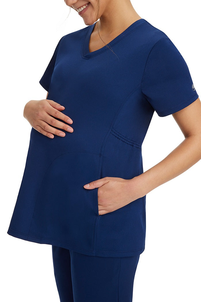 A female healthcare professional wearing an HH-Works Women's Mila Maternity V-Neck Scrub Top in Navy featuring two side seam pockets.