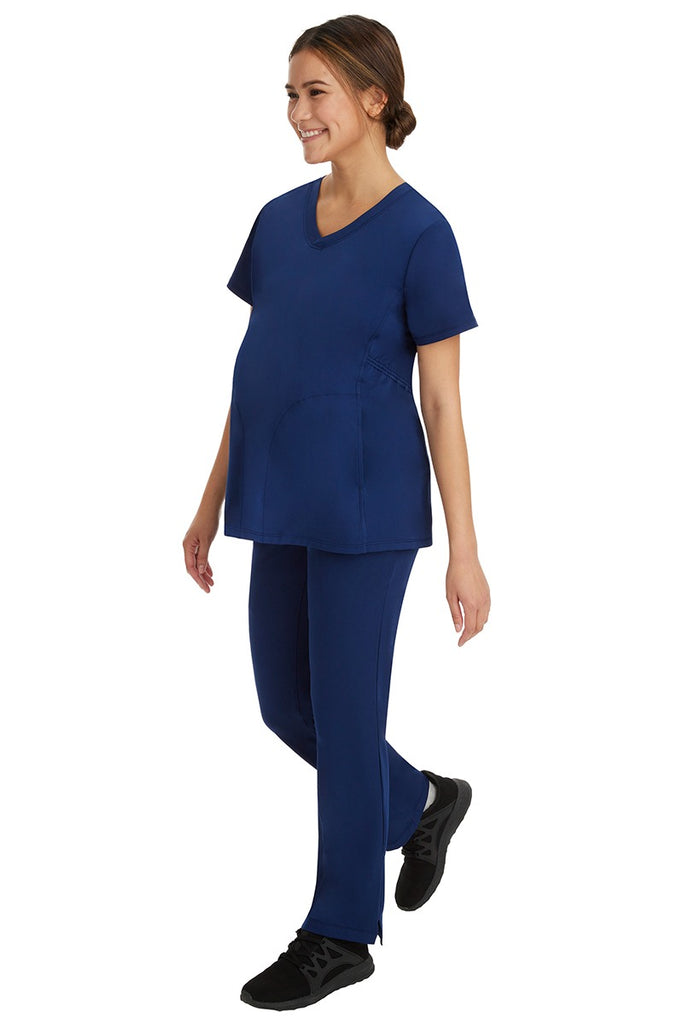 A young female healthcare worker wearing a HH-Works Women's Mila Maternity V-Neck Scrub Top in Navy featuring a unique stretch fabric made of 91% Polyester & 9% Spandex.