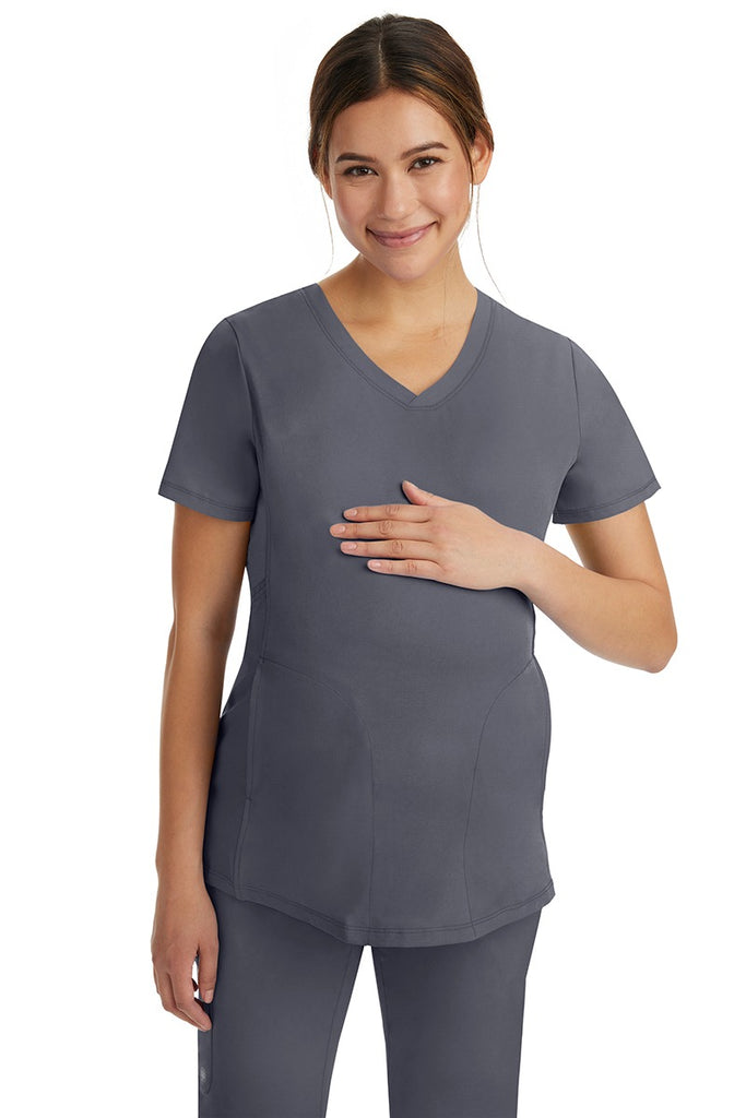 A pregnant female LPN wearing an HH-Works Women's Mila Maternity V-Neck Scrub Top in Pewter featuring a v-neckline & short sleeves.