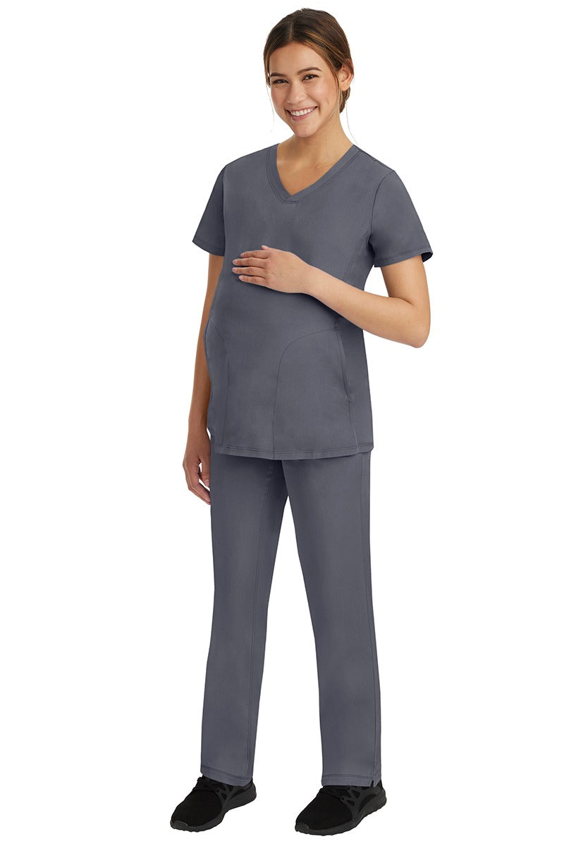A young female healthcare worker wearing a HH-Works Women's Mila Maternity V-Neck Scrub Top in Pewter featuring a unique stretch fabric made of 91% Polyester & 9% Spandex.