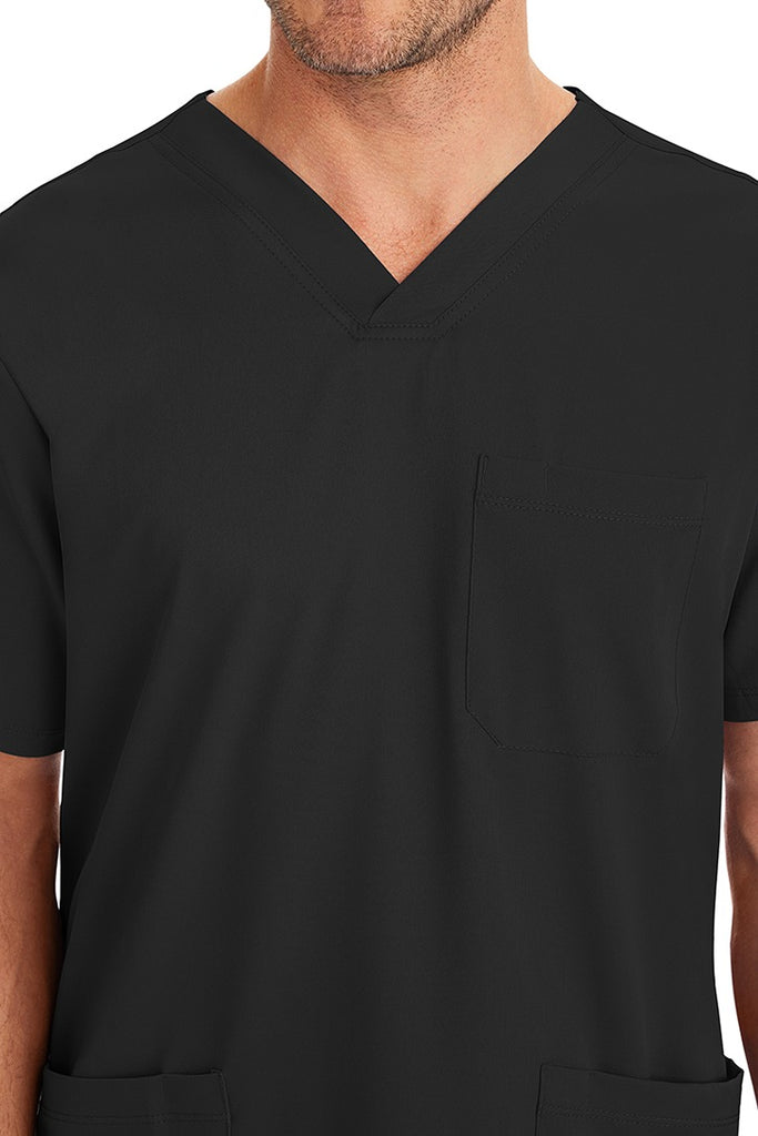 A young male CNA wearing an HH-Works Men's Matthew V-Neck Scrub Top in Black featuring a single chest pocket on the wearer's left side.