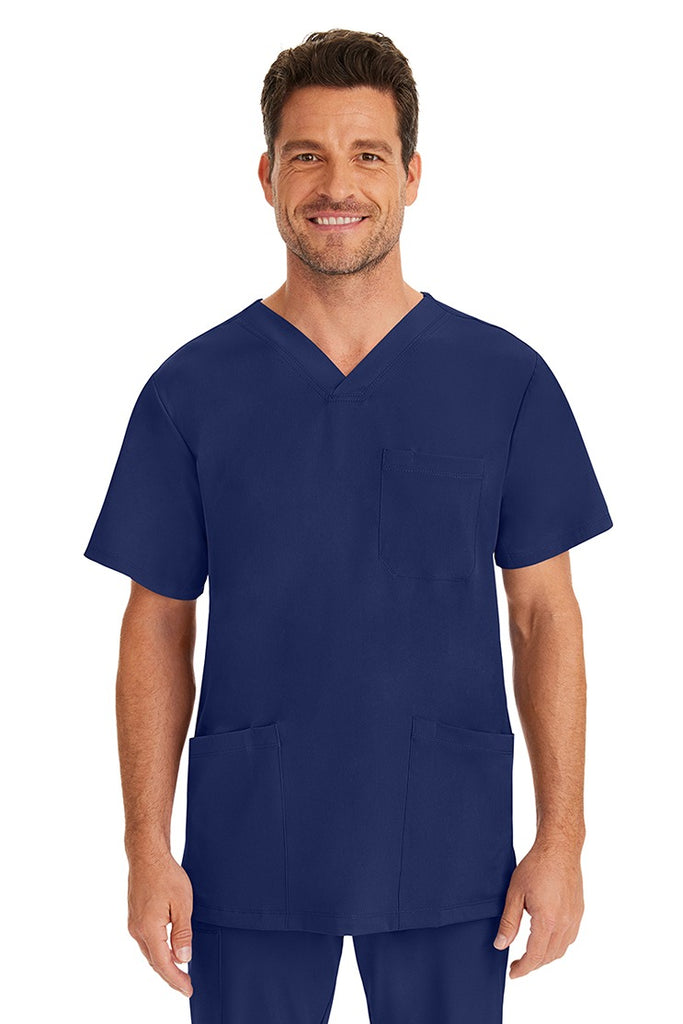 A young male nurse wearing an HH-Works Men's Matthew V-Neck Scrub Top in Navy featuring a v-neckline & short sleeves.