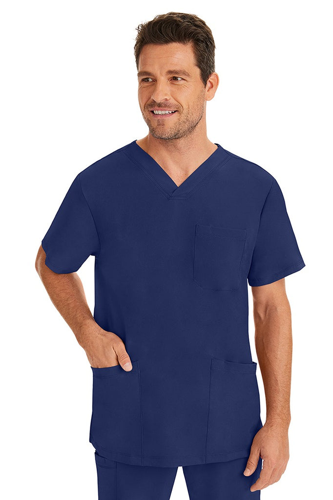 A male healthcare professional wearing an HH-Works Men's Matthew V-Neck Scrub Top in Navy  featuring a total of 4 pockets. for all your on the job storage needs.