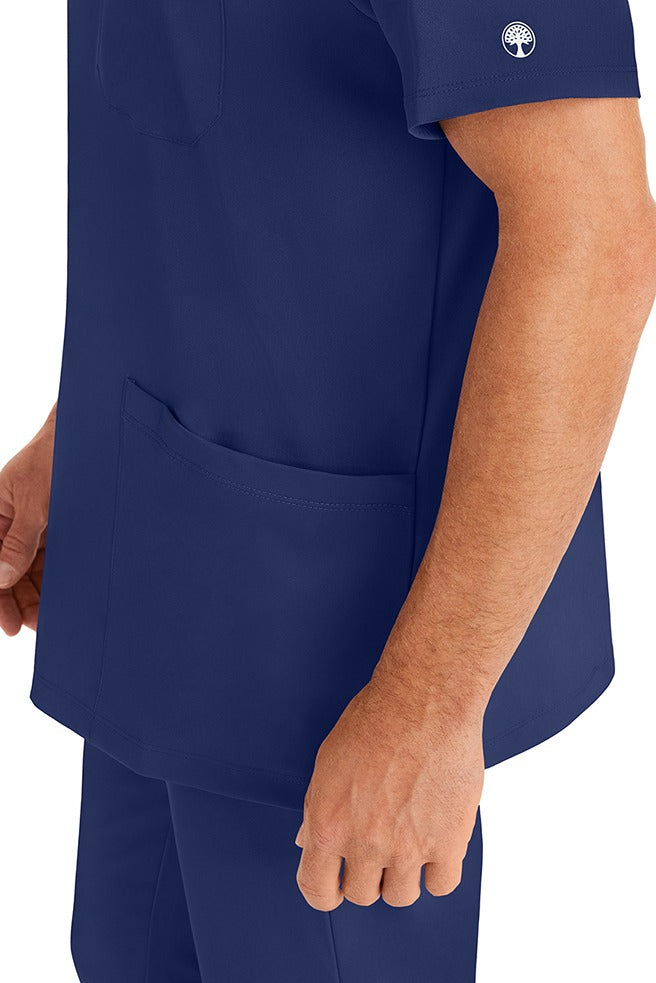 A young man wearing an HH-Works Men's Matthew V-Neck Scrub Top in Navy featuring a quick drying, moisture wicking fabric.