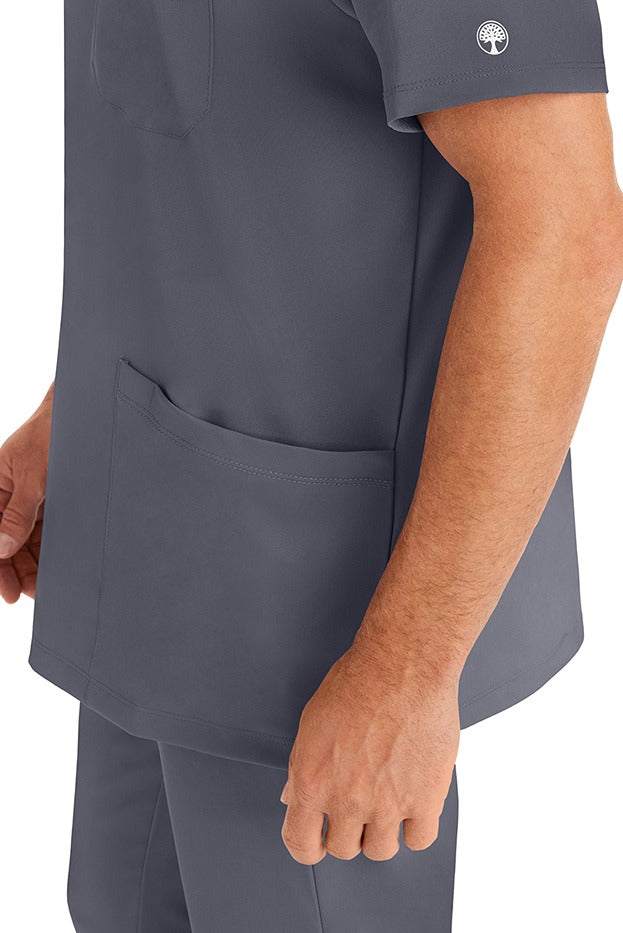 A young man wearing an HH-Works Men's Matthew V-Neck Scrub Top in Pewter featuring a quick drying, moisture wicking fabric.