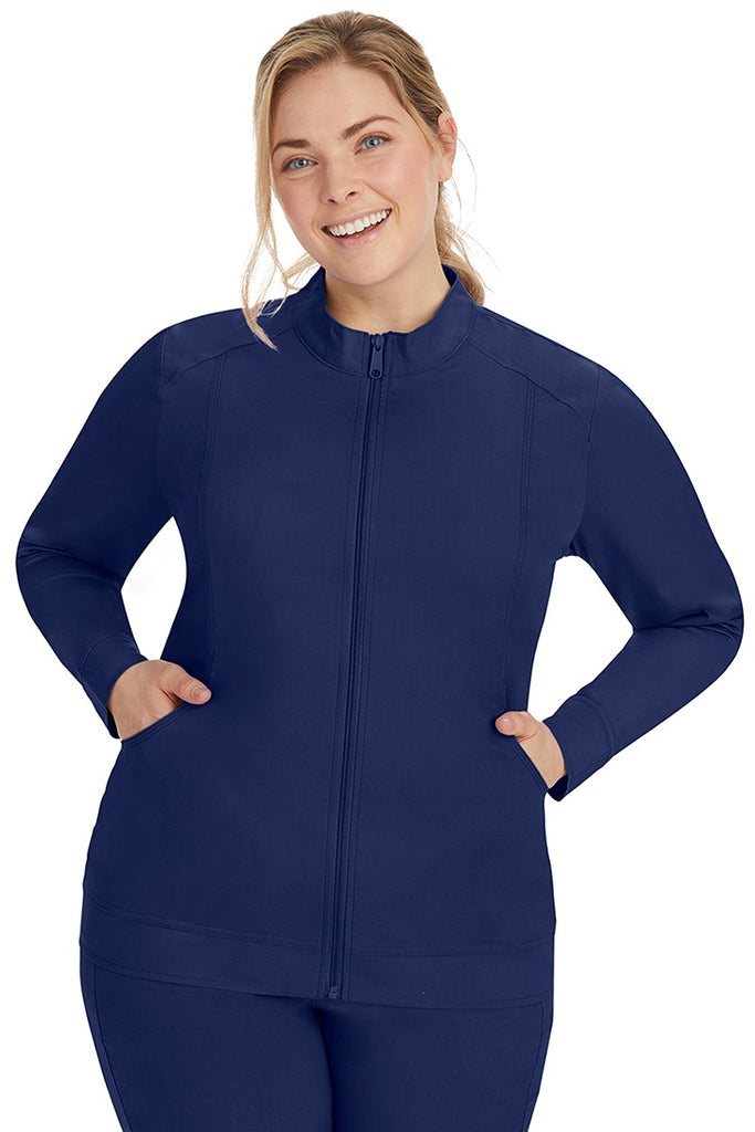A female CNA wearing a Purple Label Women's Dakota Zip Up Scrub Jacket in Navy featuring 2 side pockets for all of your on the job storage needs.
