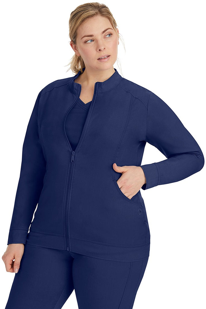 A young LPN wearing a Purple Label Women's Dakota Zip Up Scrub Jacket in Navy featuring a super comfortable fabric made of 77% Polyester/20% Rayon/3% Spandex.