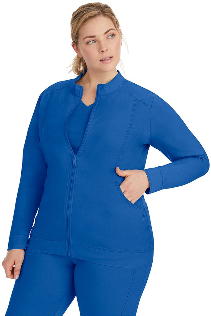 A young Home Care Registered Nurse wearing a Purple Label Women's Dakota Zip Up Scrub Jacket in Royal featuring a zipper pull closure with opening for attaching ID.