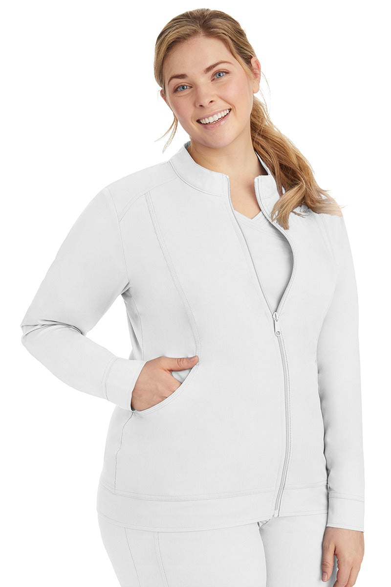 A young Home Care Registered Nurse wearing a Purple Label Women's Dakota Zip Up Scrub Jacket in White featuring a zipper pull closure with opening for attaching ID.