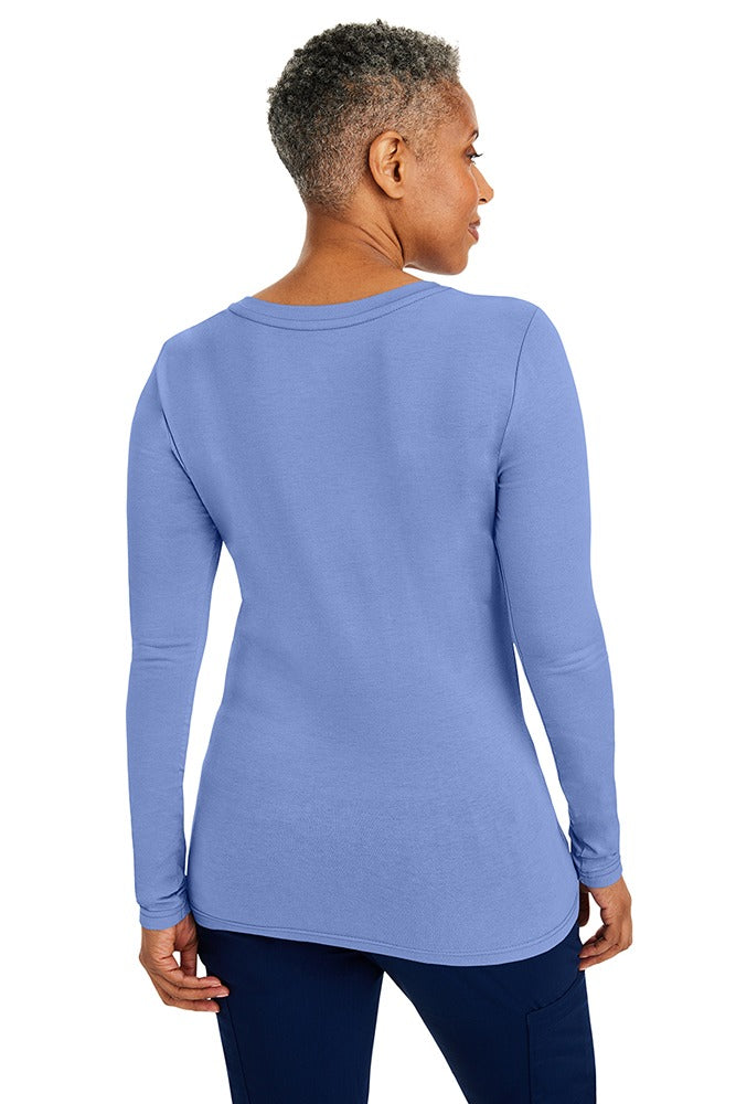 A woman Registered Nurse wearing a Purple Label Women's Melissa Long Sleeve T-Shirt in Ceil featuring a a superior cotton-polyester-spandex stretch fabric blend that is lightweight, soft and breathable.