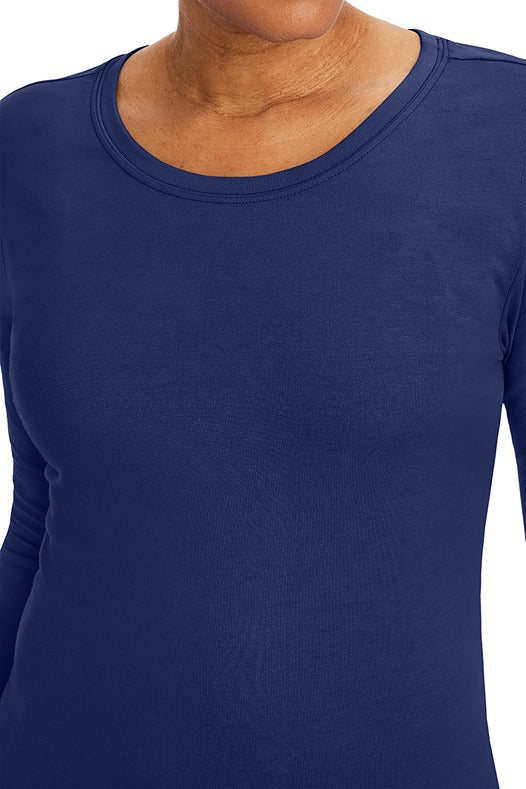 A lady nurse practitioner wearing a Purple Label Women's Melissa Long Sleeve T-Shirt from Healing Hands in Navy featuring a super comfortable fabric blend that resists wrinkles, shrinking, and fading better than traditional cotton scrubs.