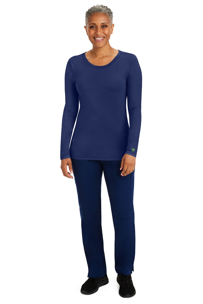 A female nurse wearing a Purple Label Women's Melissa Long Sleeve T-Shirt from Healing Hands in Navy featuring a banded crew neckline.