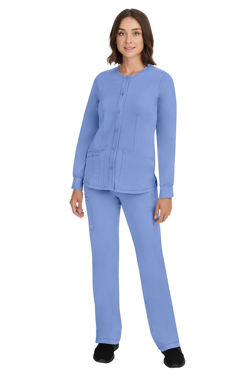 A young female Home Care Registered Nurse wearing an HH-Works Women's Megan Snap Front Scrub Jacket in Ceil featuring yoga knit cuffs to ensure a flattering and comfortable fit.