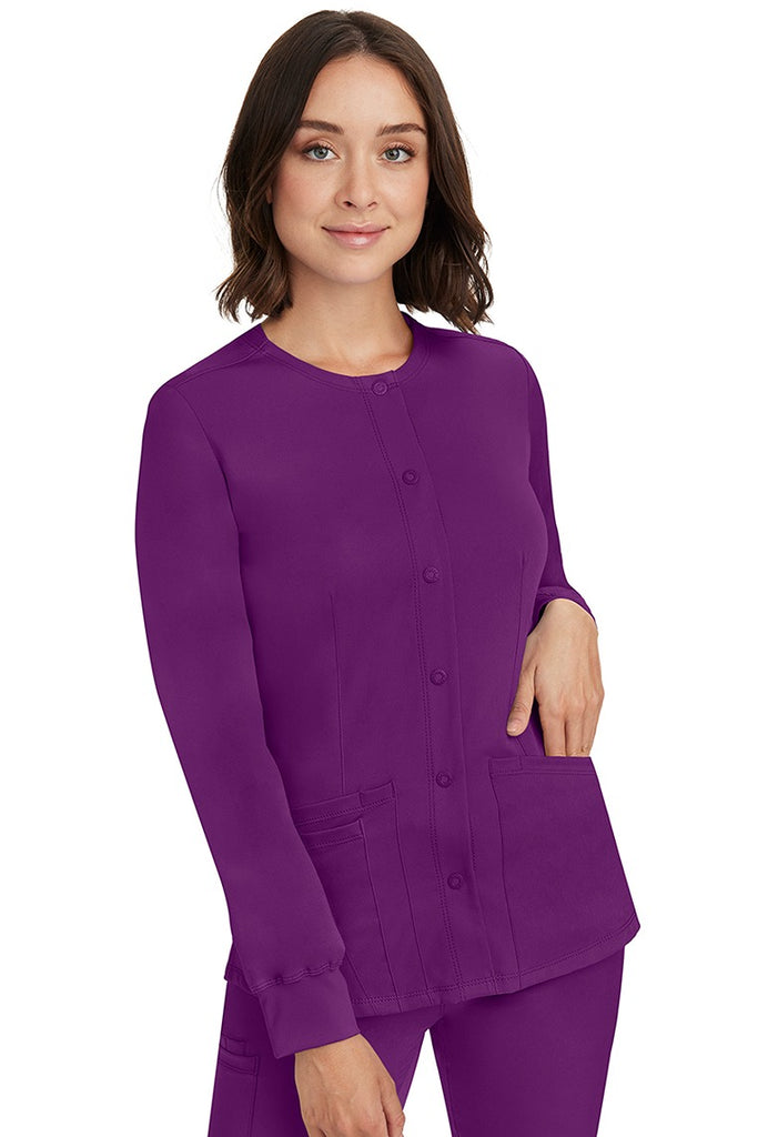 A young lady RN wearing an HH-Works Women's Megan Snap Front Scrub Jacket in Eggplant featuring front princess seaming to ensure a flattering fit.