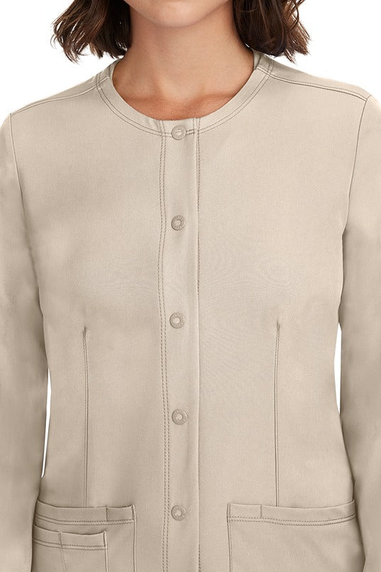 A female LPN wearing a Women's Megan Snap Front Scrub Jacket from HH Works in Khaki featuring a snap-up button front closure.